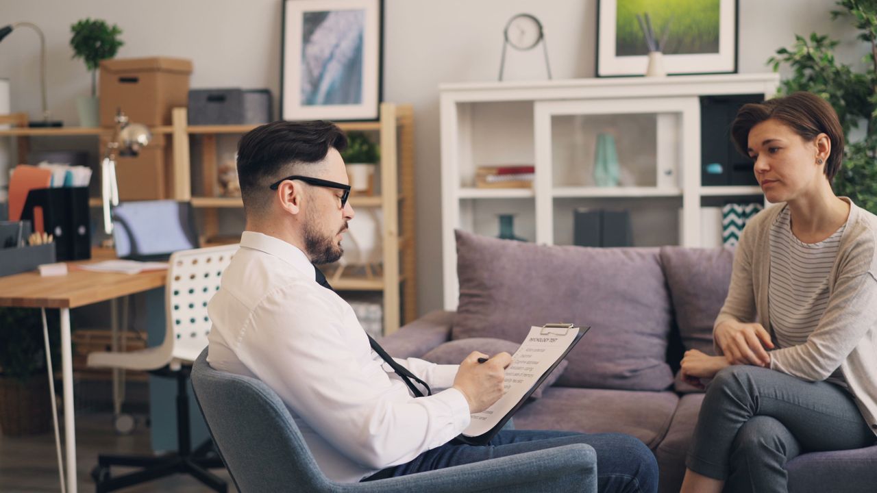 The Art of Drawing Readers In: Your attractive post title goes here A therapist engages in a consultation session with a female patient in a cozy office setting.